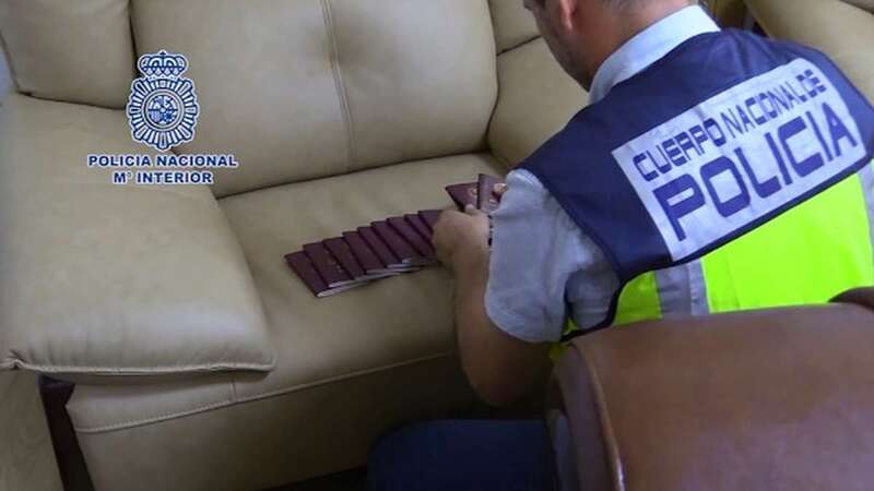 Un policía cuenta los pasaportes falsos recogidos en el piso de Valencia (Foto CNP)